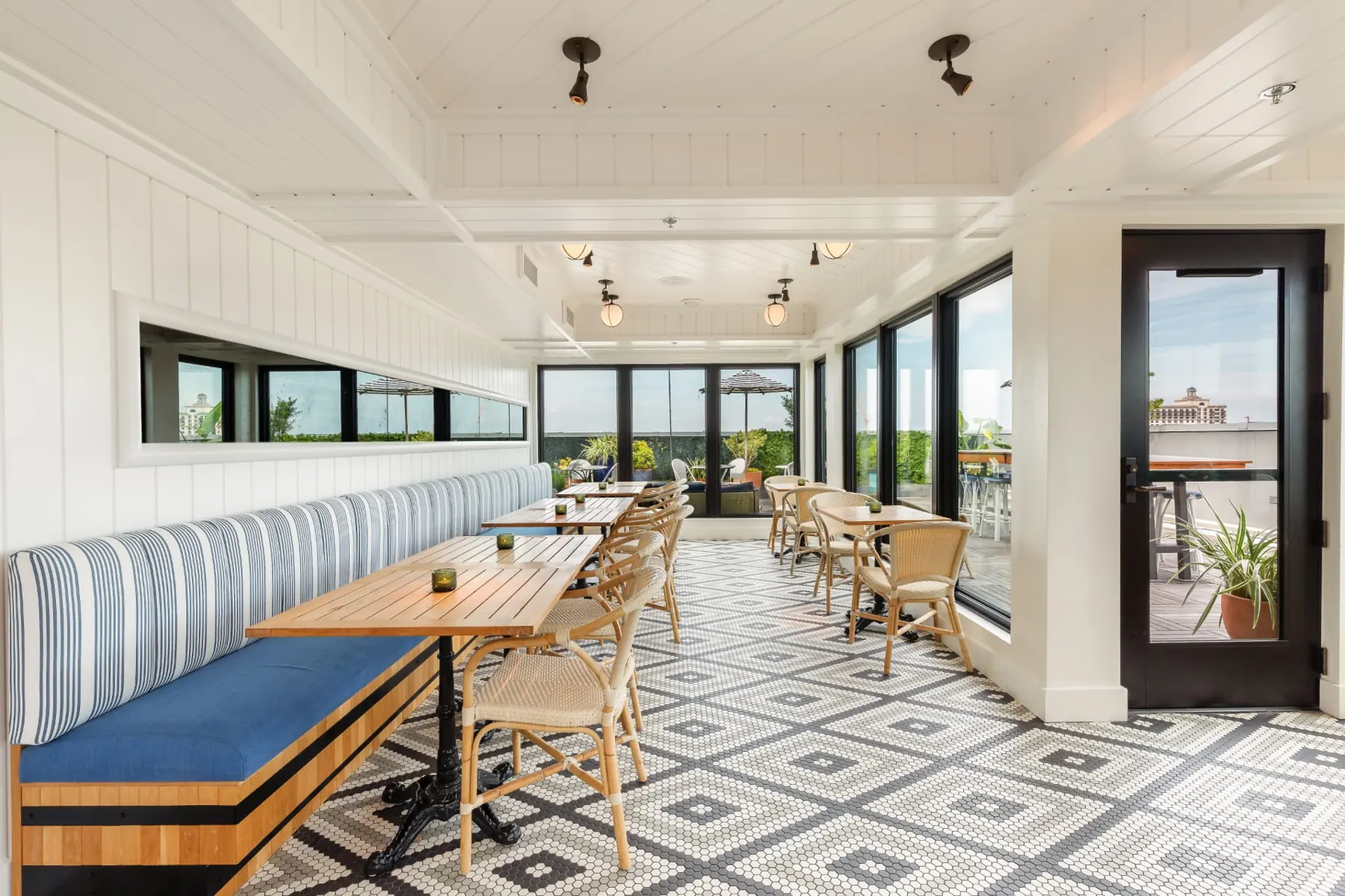 Striped banquette and wood tables in the sunlit indoor room